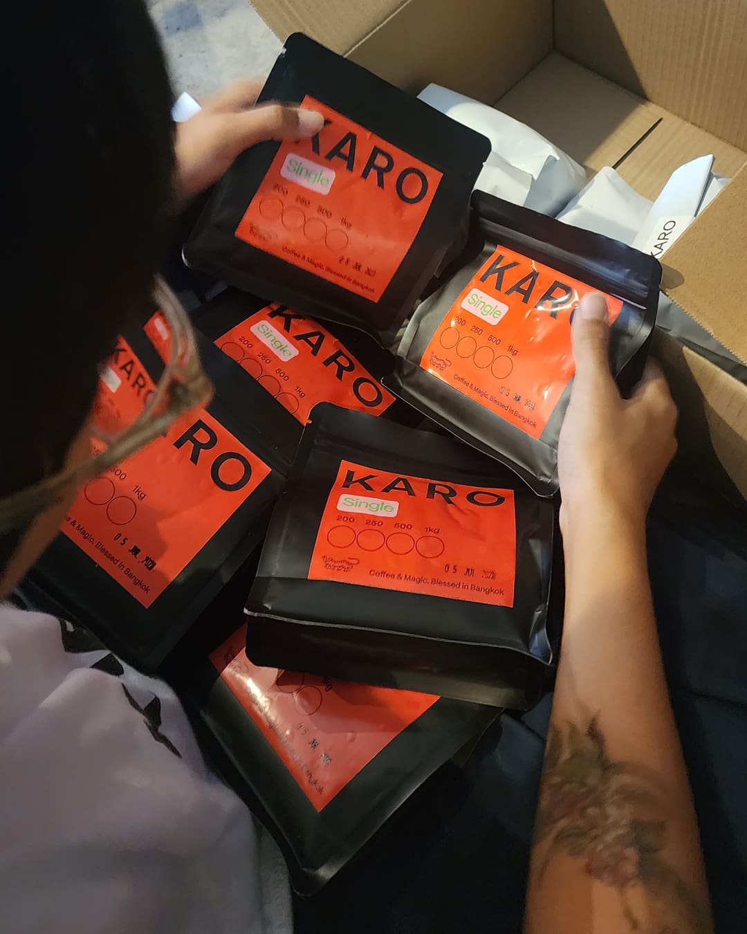 Bags of Karo Coffee Roasters coffee in red and black packaging.