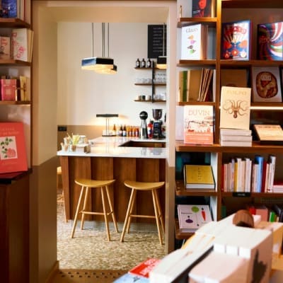 A selection of books on display on wooden bookcases at Tram Cafe Paris, framing an entrance into a coffee bar area.
