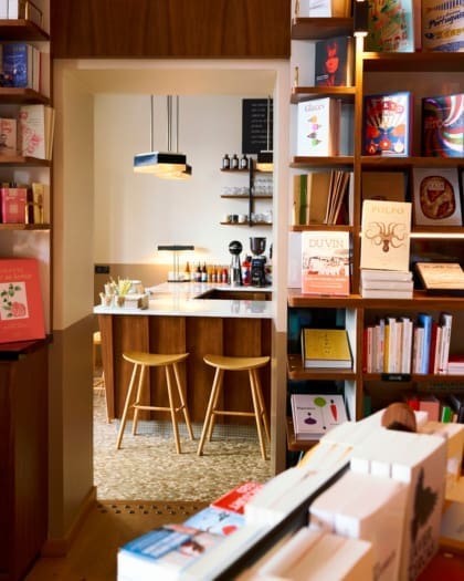 A selection of books on display on wooden bookcases at Tram Cafe Paris, framing an entrance into a coffee bar area.