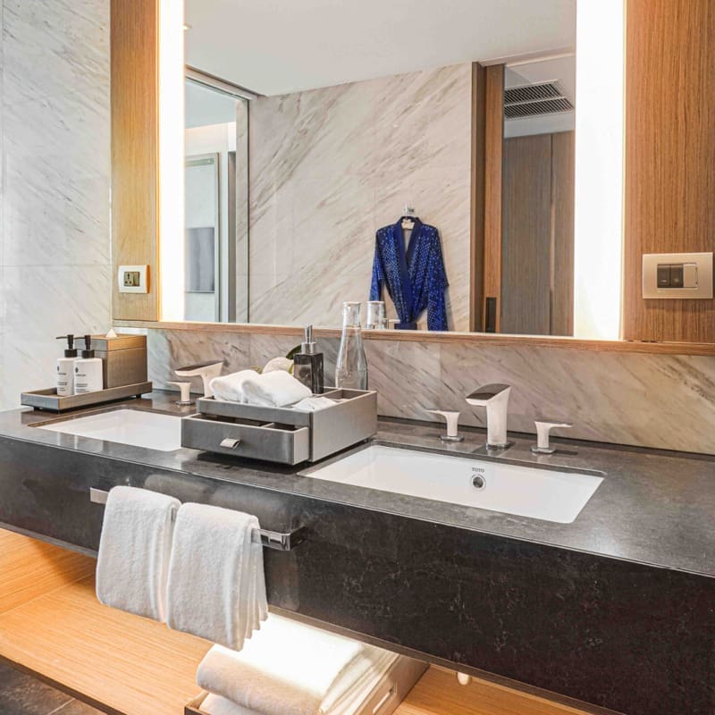 bathroom with twin vanity unit, large mirror and hanging robe in a three bedroom suite