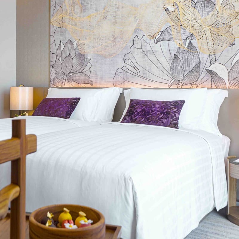 twin beds with luxury white linen, wall art and decorations in a two bedroom suite