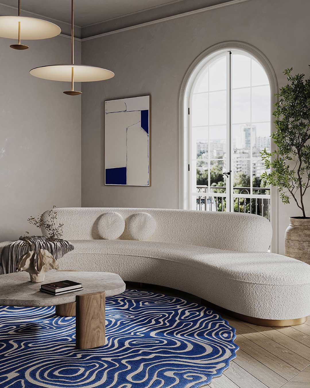 A boucle wool sofa with round cushions sits behind a blue wavy rug and wooden table with an arched window behind in Hatsu design shop, Mumbai.