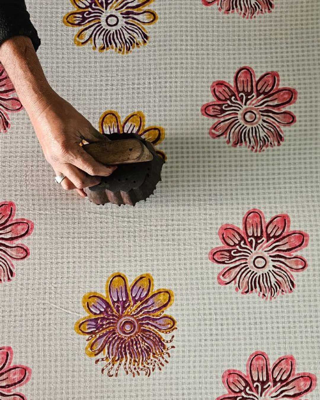 A hand uses a wooden block to print a colourful flowery motif on a textile at Jodi boutique in Mumbai.