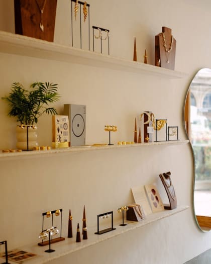 Jewellery arranged along three white shelves on a white wall in Lune boutique in Mumbai.