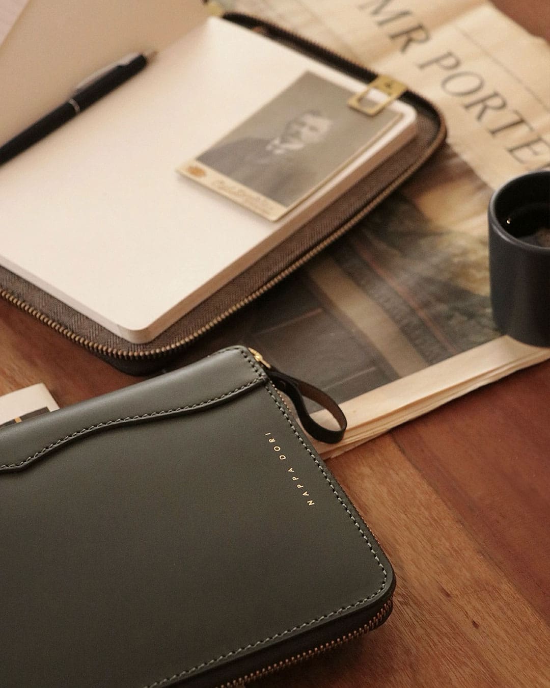 A leather notebook sits on a wooden table next to a Mr Porter newspaper at Nappa Dori boutiqe in Mumbai.