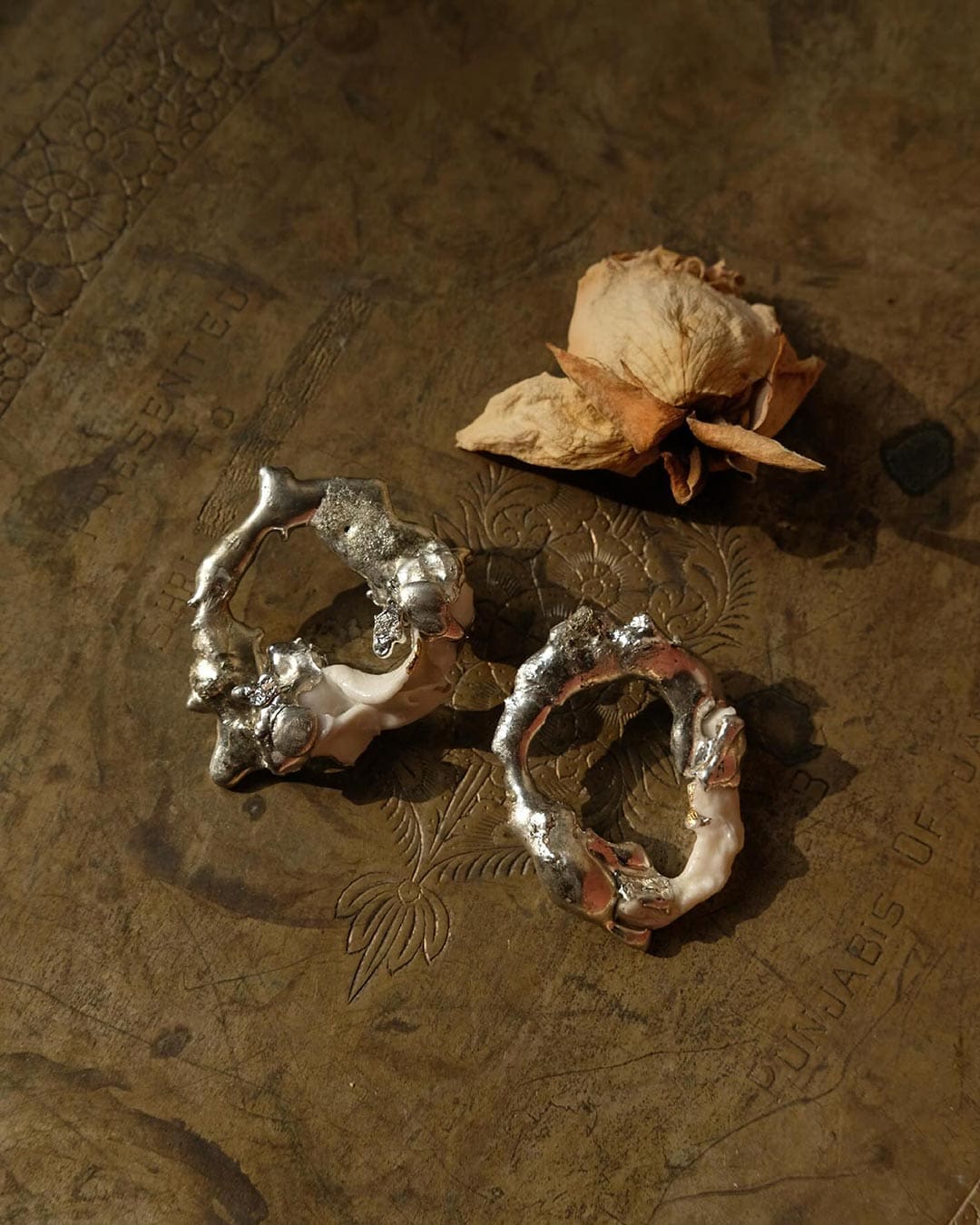 Two pieces of jewellery on a dark brown surface at Two Extra Lives boutique in Mumbai.