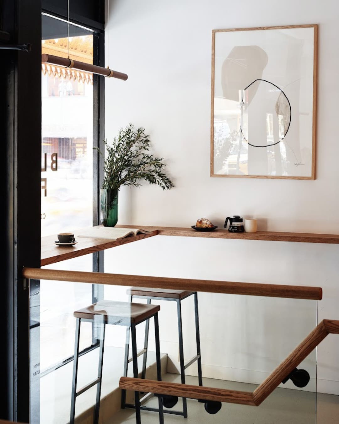 Minimal white walls, wooden shelving and stalls inside Black Fox Coffee shop in New York.
