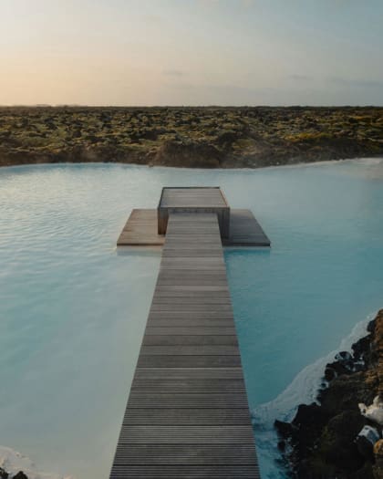 A wooden platform extends into blue water at the Blue Lagoon in Iceland, an accessible travel destination.