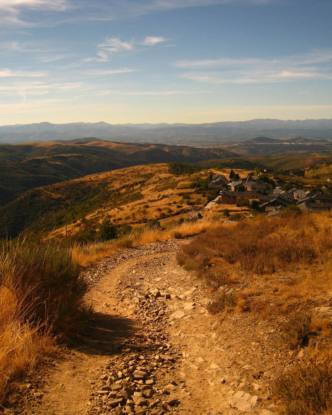 A gravelly portion of the Camino de Santiago trail threading its way through hills.