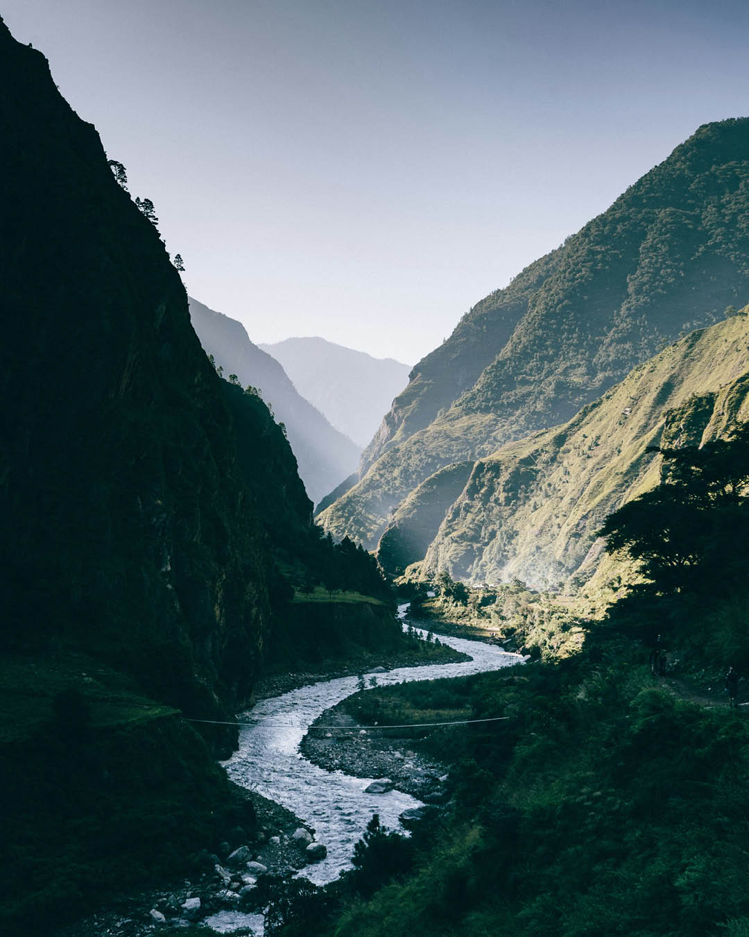 A hiking trail follows a river through the Himalays.