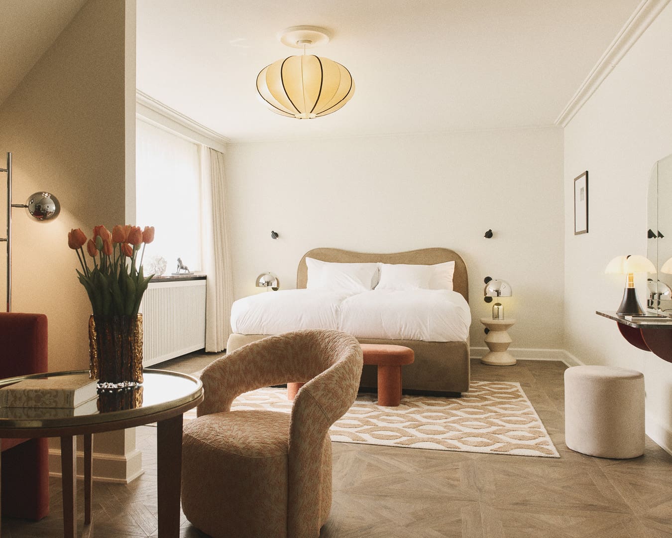 Muted tones, cushion-like lamps, statement chairs and an airy finish seen in a bedroom at Hotel Bella Grande