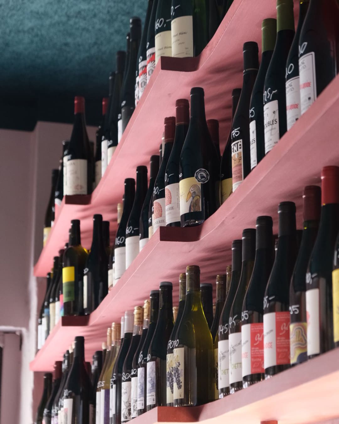 Pink shelves stacked with natural wines at Josephine bar