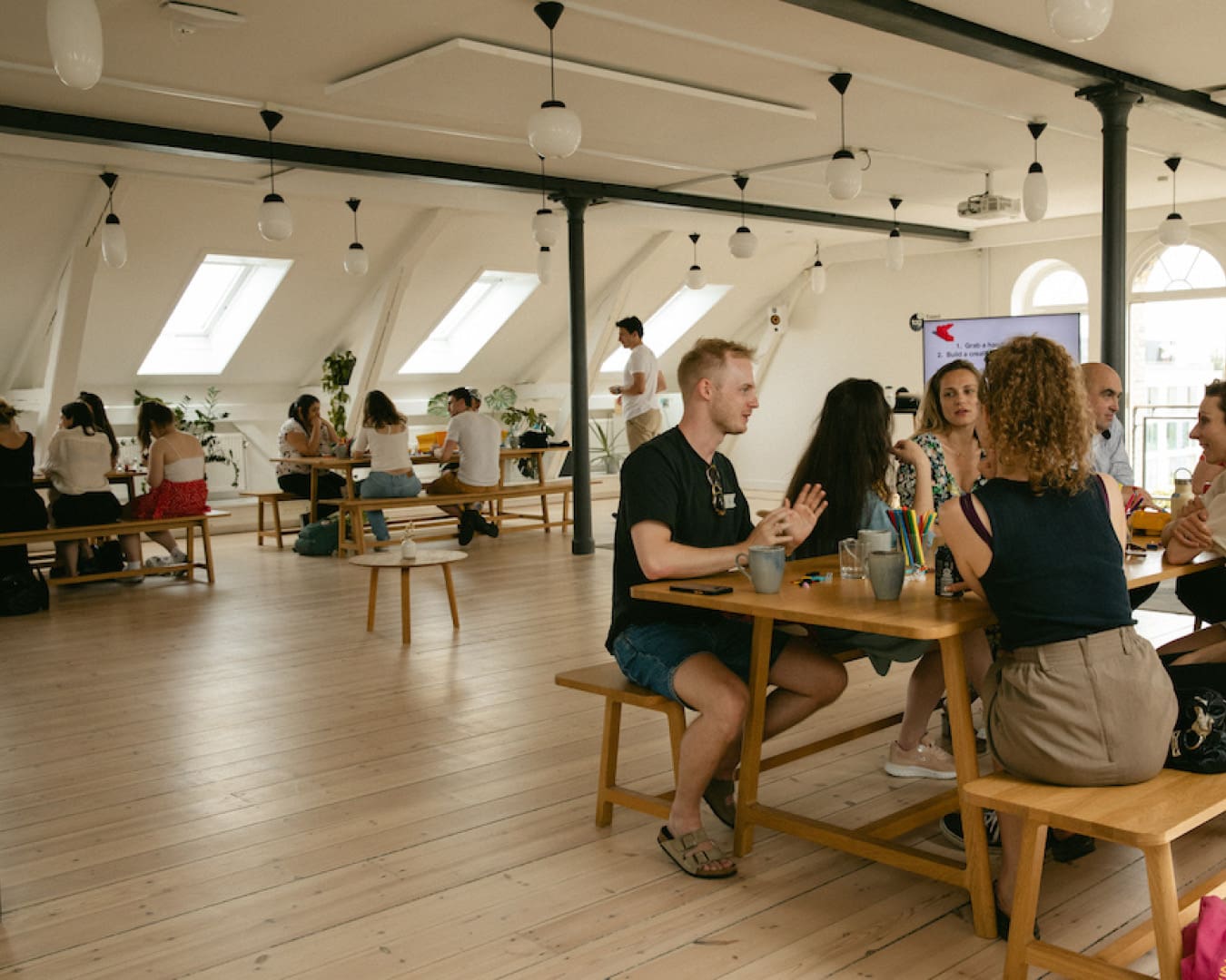 People chat over tables at Talent Garden Rainmaking co-working space in Copenhagen.