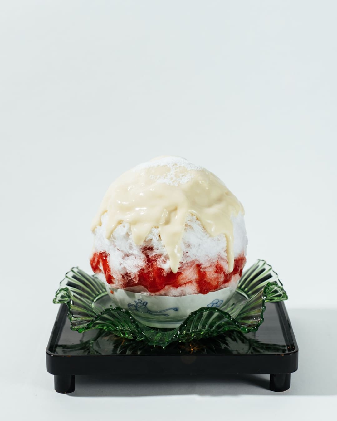 A ball of strawberry shaved ice served on a green ornamental glass plate in Tasuki cafe, Kyoto.