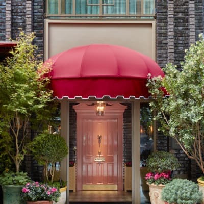 The grand and glorious pink front door at Broadwick Soho hotel in London, framed by potted plants and flowers