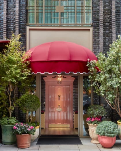 The grand and glorious pink front door at Broadwick Soho hotel in London, framed by potted plants and flowers