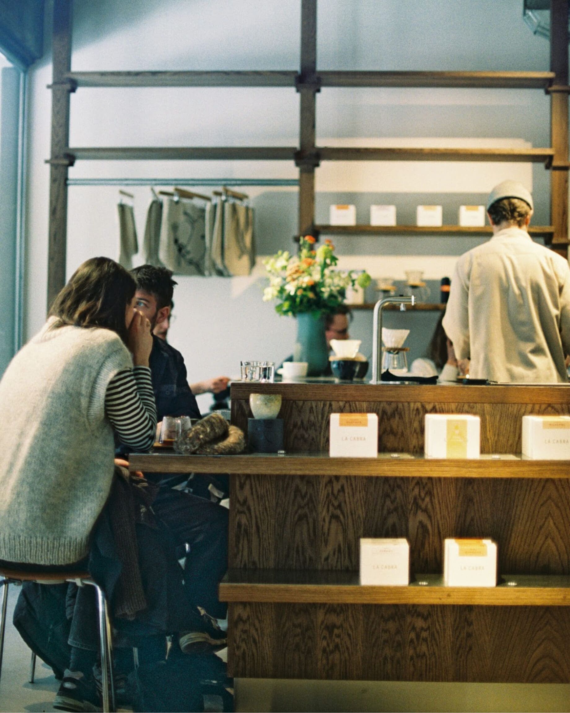 Two people sat at the wooden bar at coffee shop La Caba in Copenhagen.