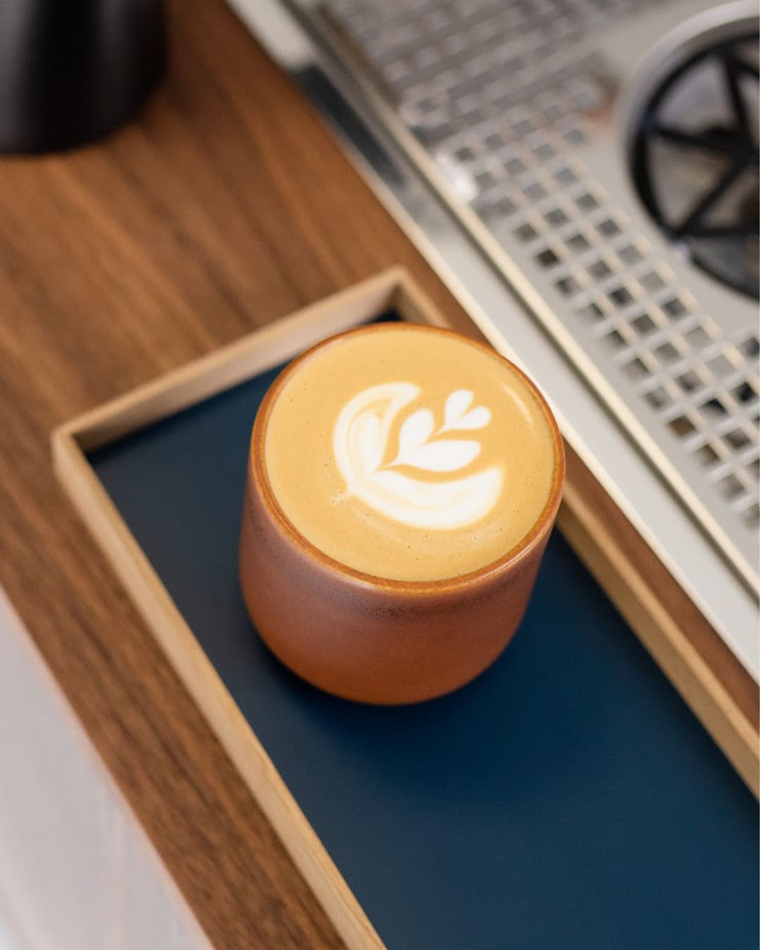 A flat white served on a wooden tray at April Coffee shop in Copenhagen.