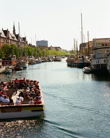 A boat full of people makes its way through the harbour in Copenhagen.