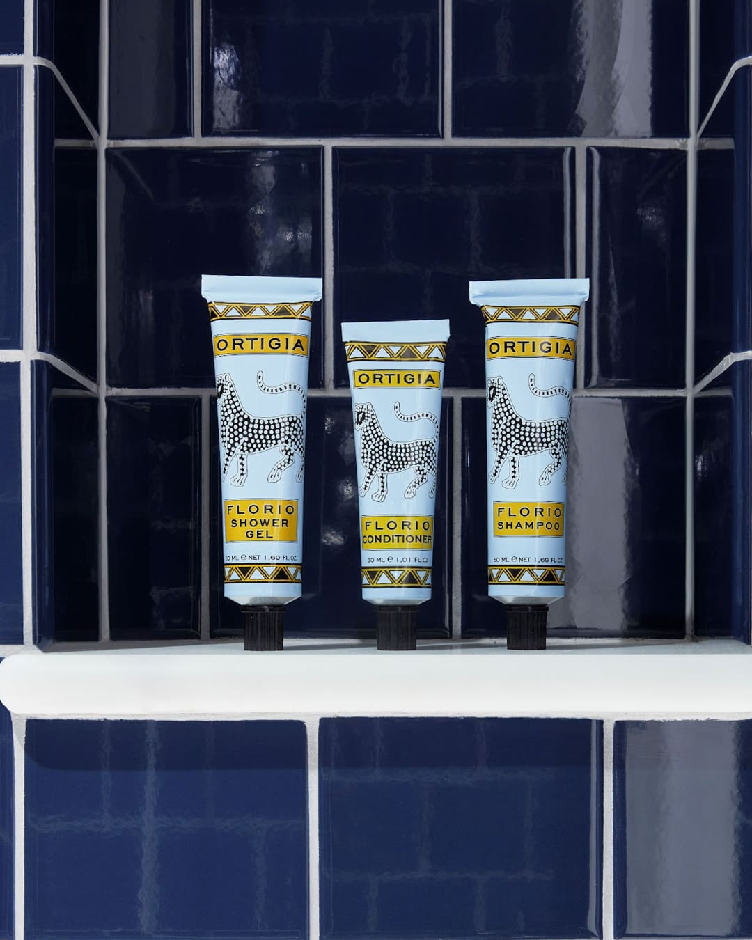 Ortigia products displayed in Broadwick Soho bathrooms, featuring elegant tubes of luxurious toiletries against a navy tiled backdrop.