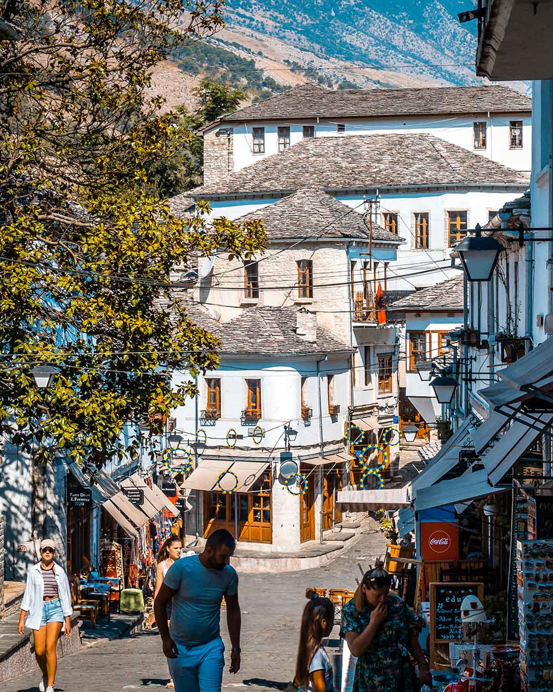 People stroll along a sun-warmed street in the small village of Gjirokastër in Albania