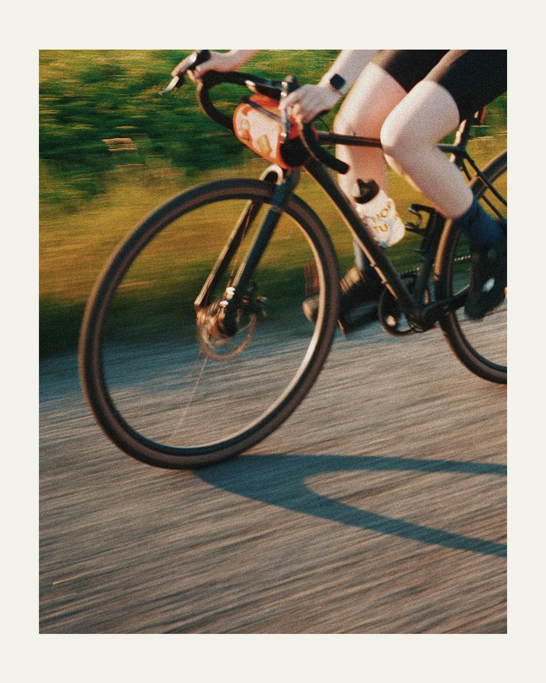 A detail of a person cycling a gravel bike over a blurred path.