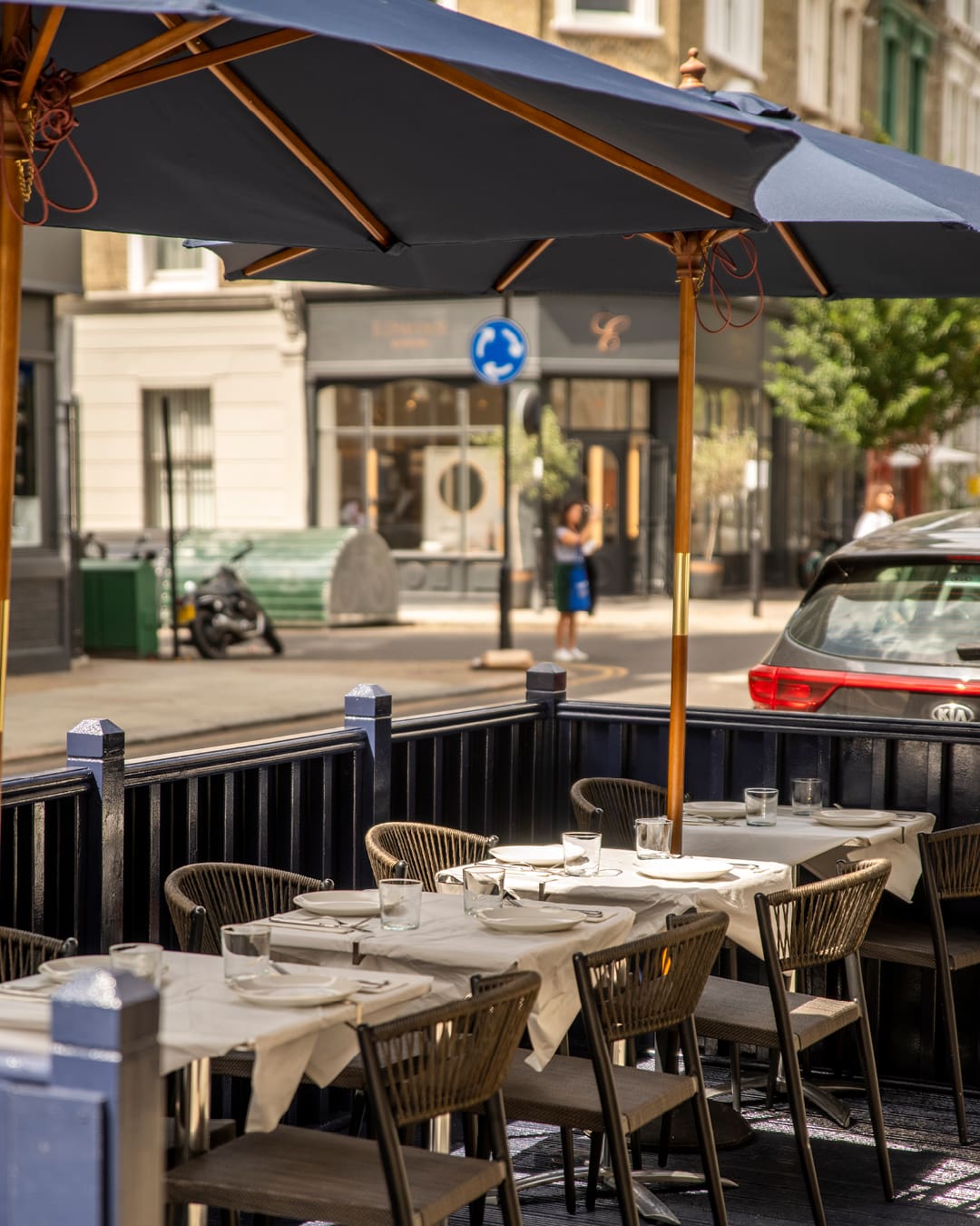 Streetside dining beneath blue parasols at Empire Empire in Notting Hill