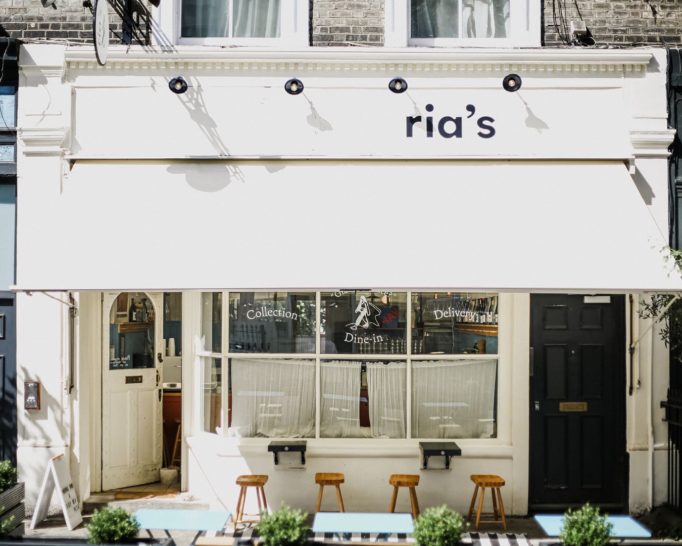 The whitewashed facade of Ria's in Notting Hill with streetside tables