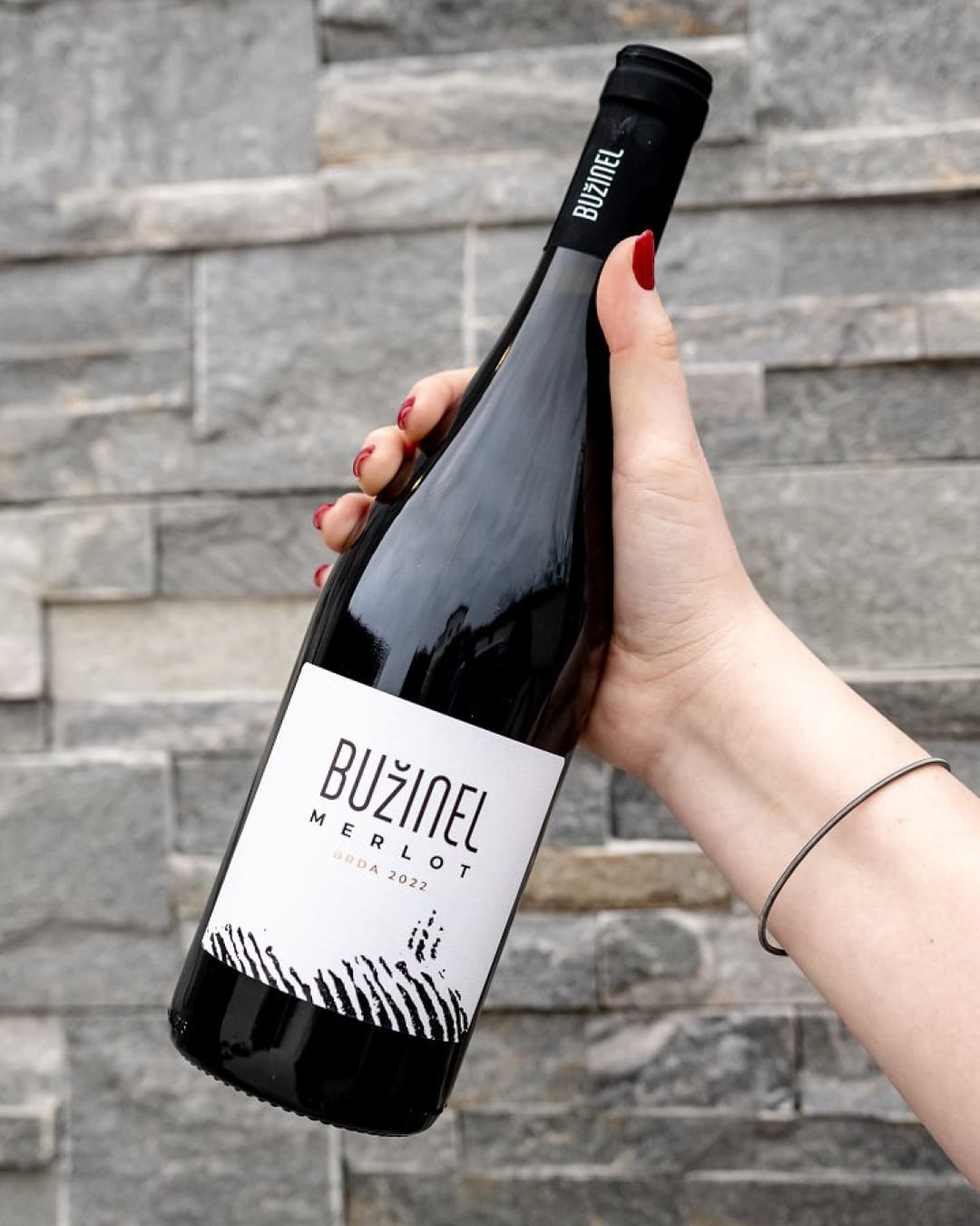 A bottle of wine from Bužinel Winery, featuring a sleek design with a white label.