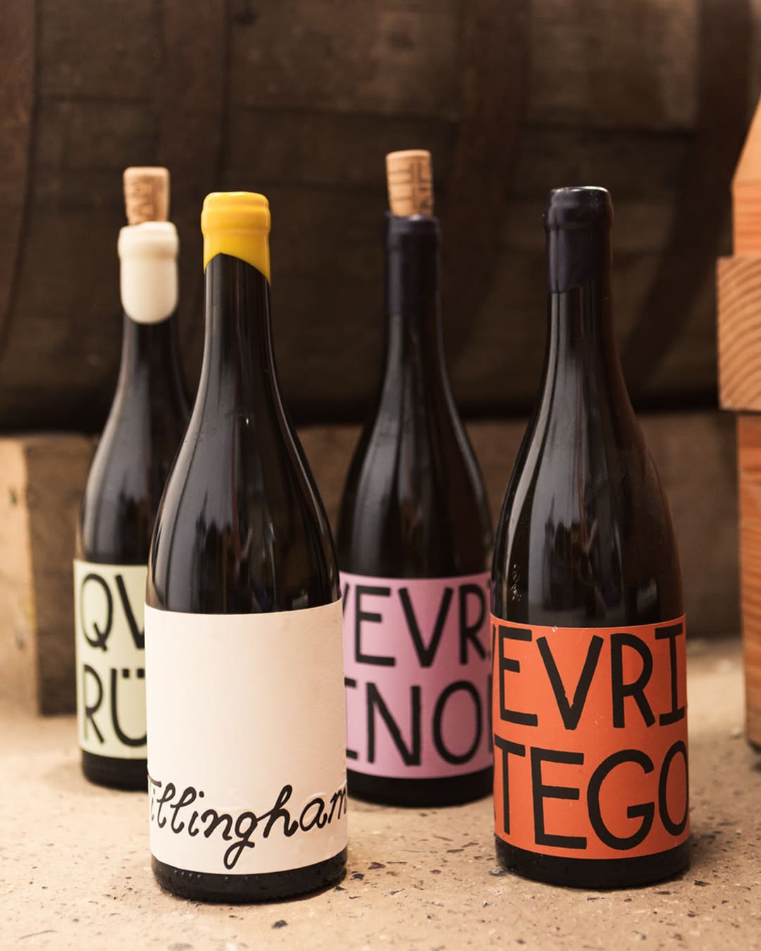 Selection of wines from Tillingham Wine, UK, featuring uniquely labeled bottles with vibrant colours and artistic designs against a rustic background.