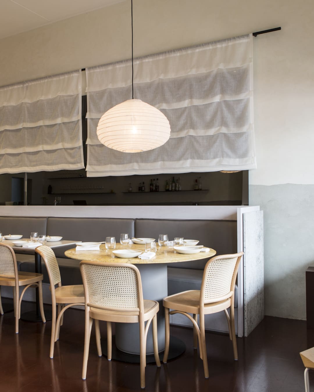 Rattan chairs, pendant lights and white linen curtains decorate the space at Anchovy in Richmond, Melbourne