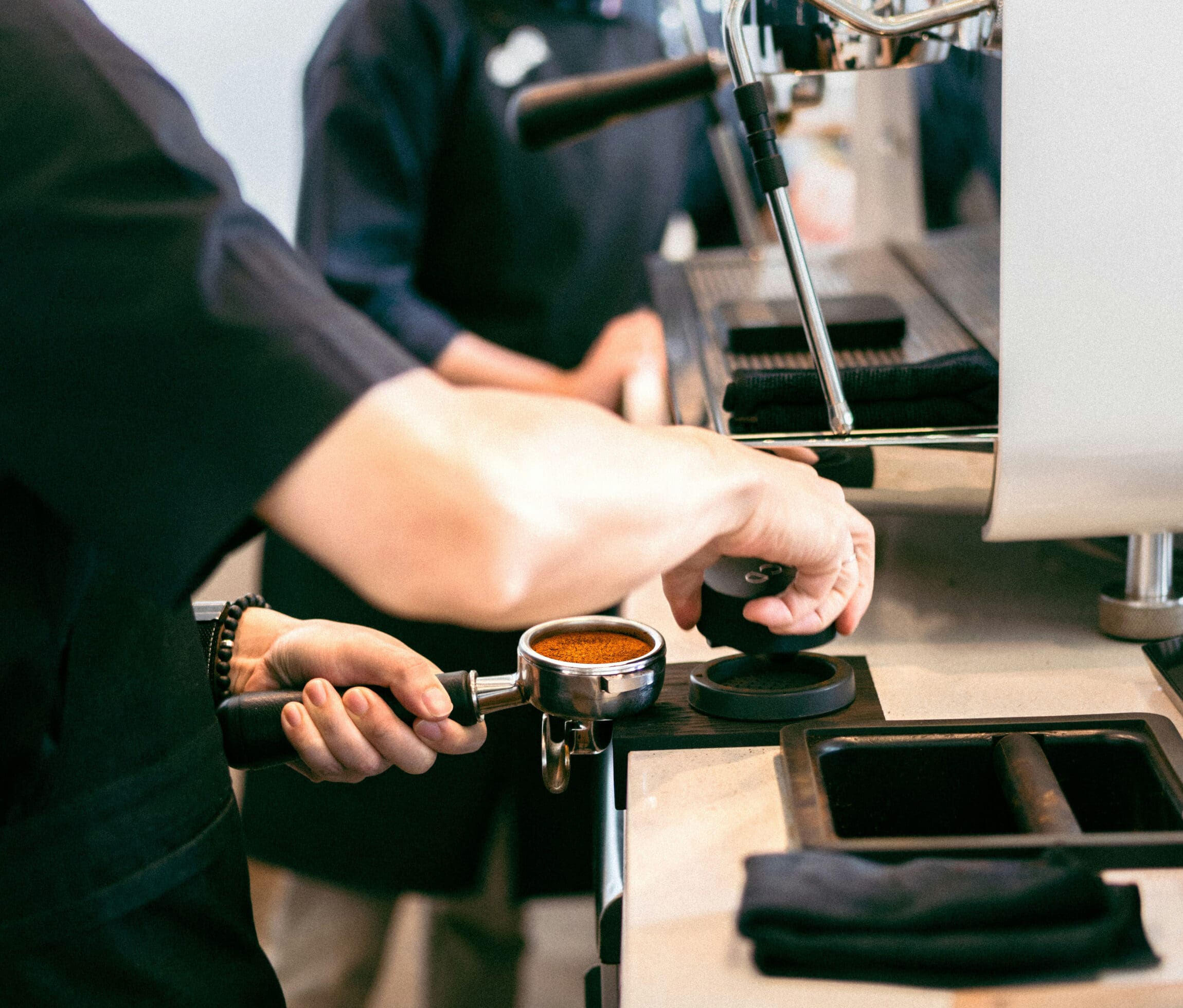 A barista tamps coffee.