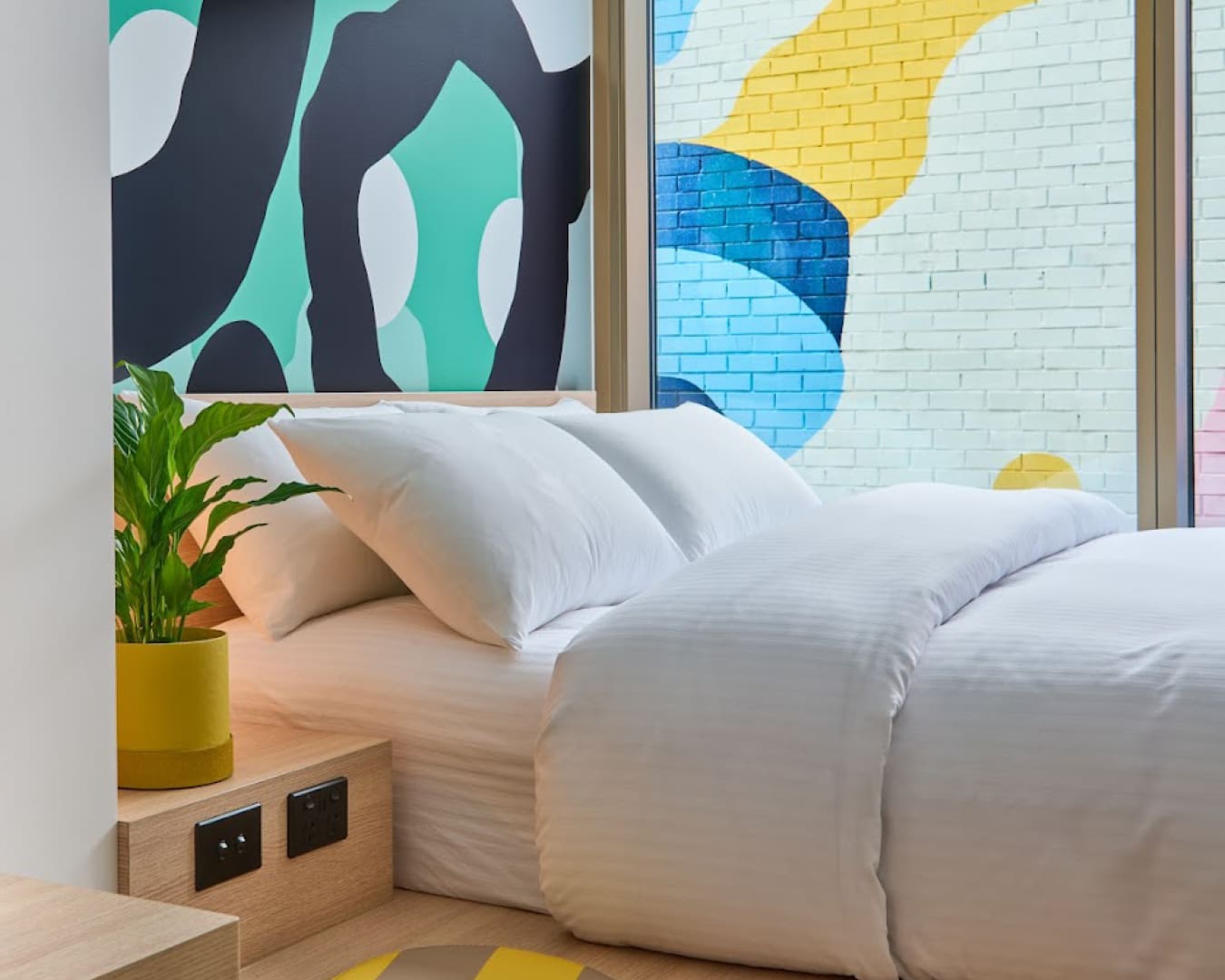 A bedroom at Lyf Collingwood with mural walls and potted plants