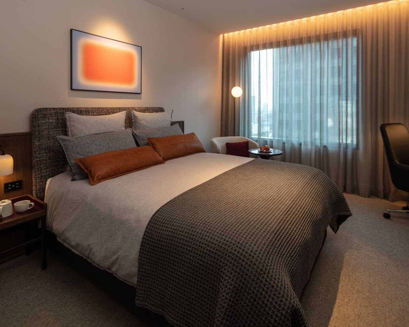 An abstract painting hangs above a double bed at Next Hotel Melbourne