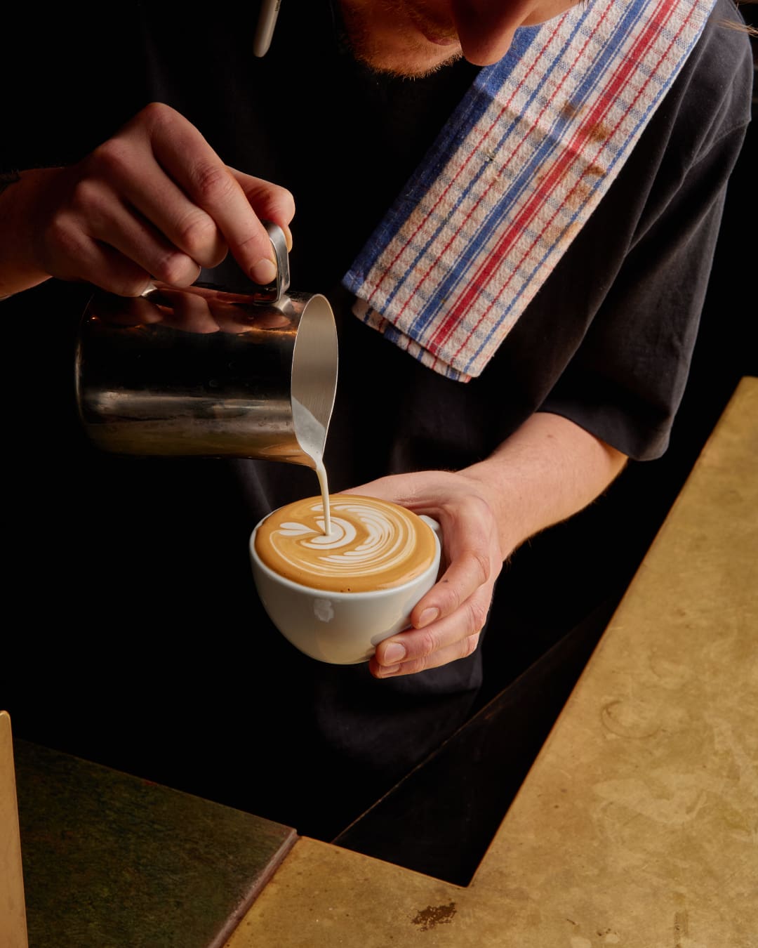 Barista making a cappucino with coffee art at Square One cafe in Melbourne.