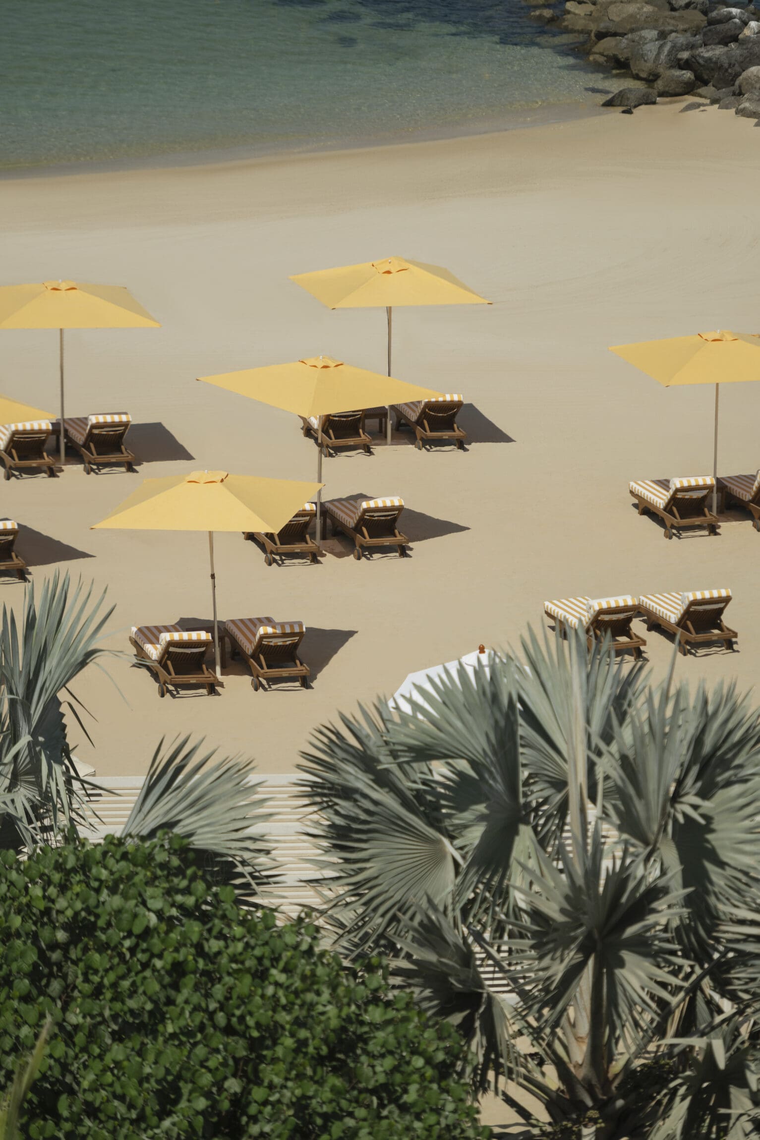 Sun loungers and yellow parasols decorate the white-sand private beach at Delano Dubai