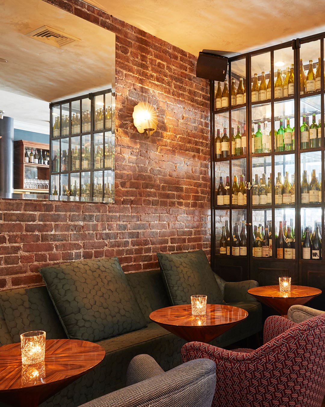 Some of La Compagnie Vins Surnaturels extensive wine collection, a warm inviting interior with candles and views to New York City, NYC