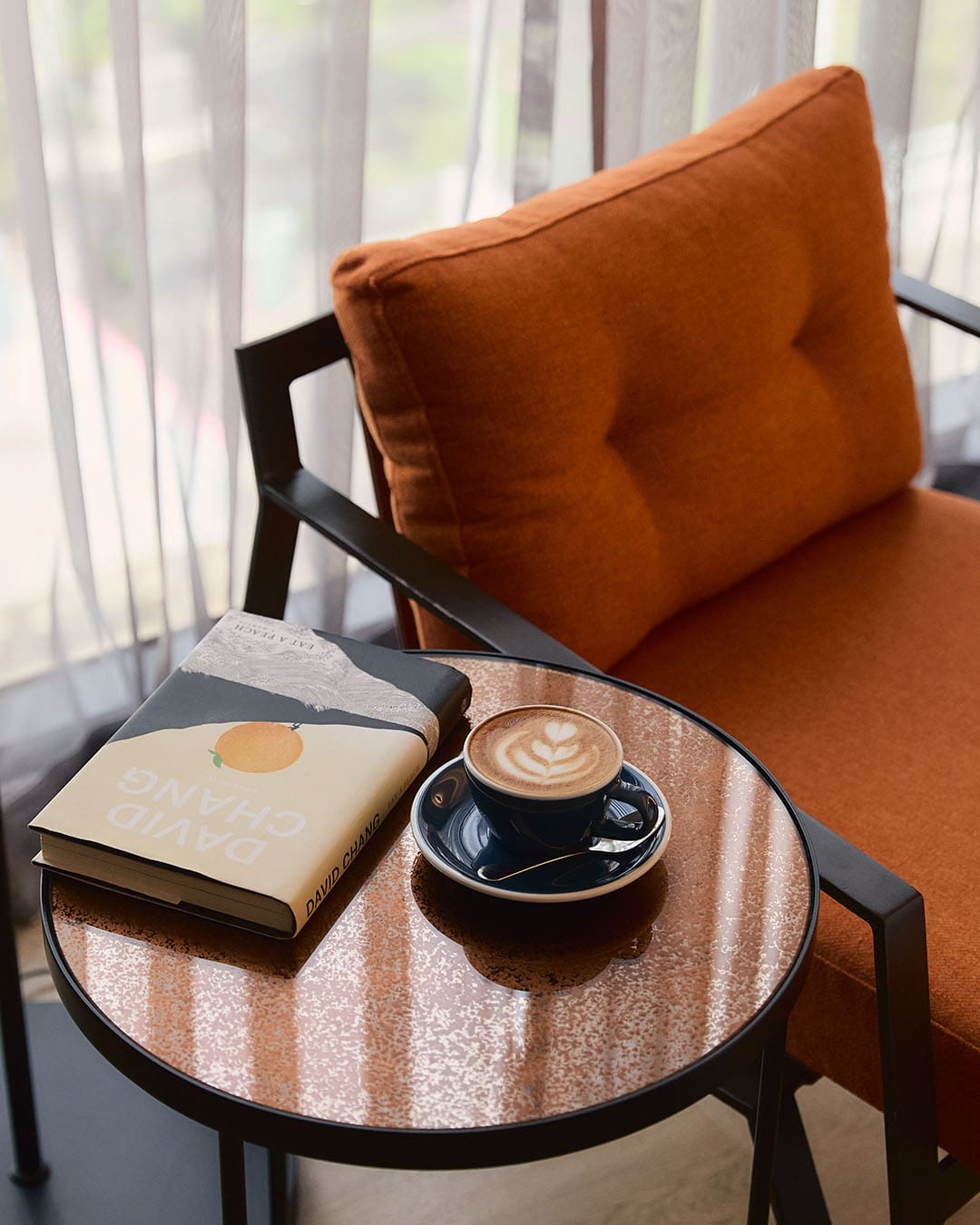 A coffee and book on a table next to a comfortable chair in the Public House coffee shop in Bangkok