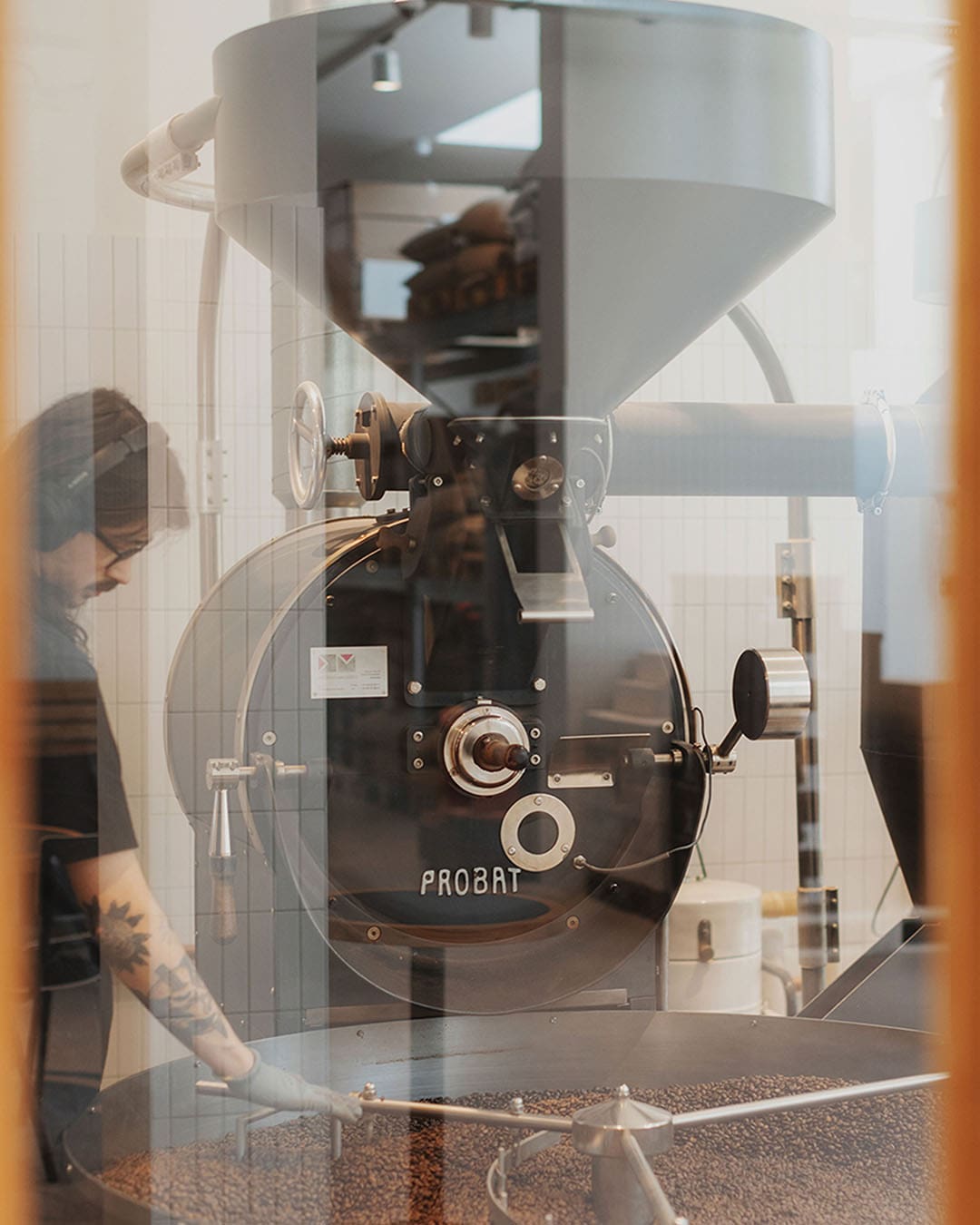 Man works at the coffee roastery, overseeing the machine at Man Met Bril Koffie, Rotterdam