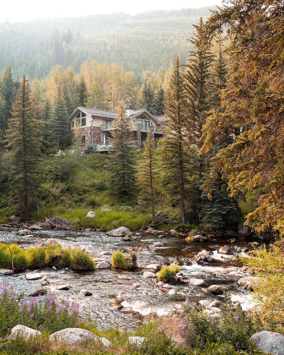The Grand Hyatt Vail is positioned on the river, sun trying to break through the clouds