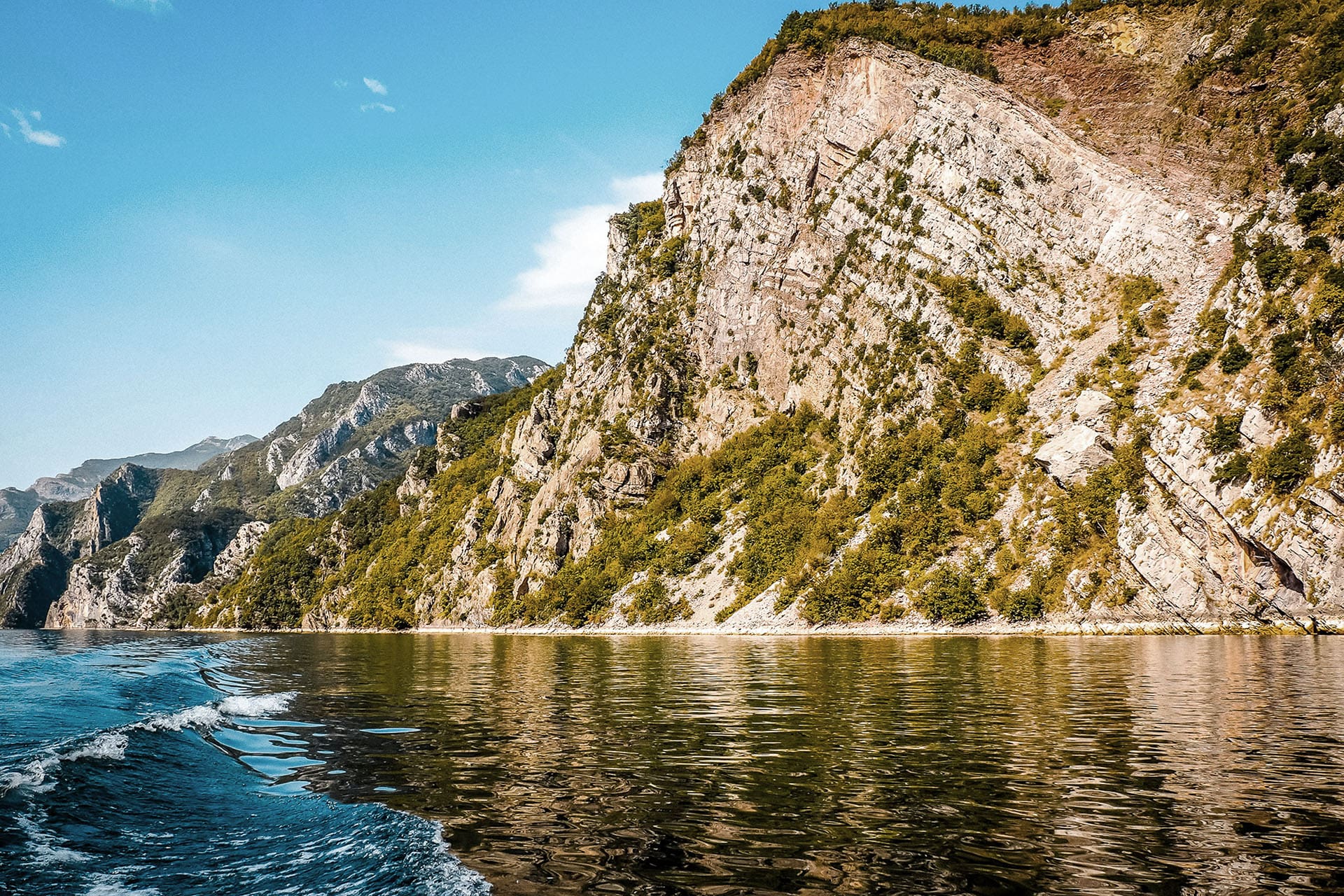 A scene taken from a boat on Lake Komani showing mountain landscapes