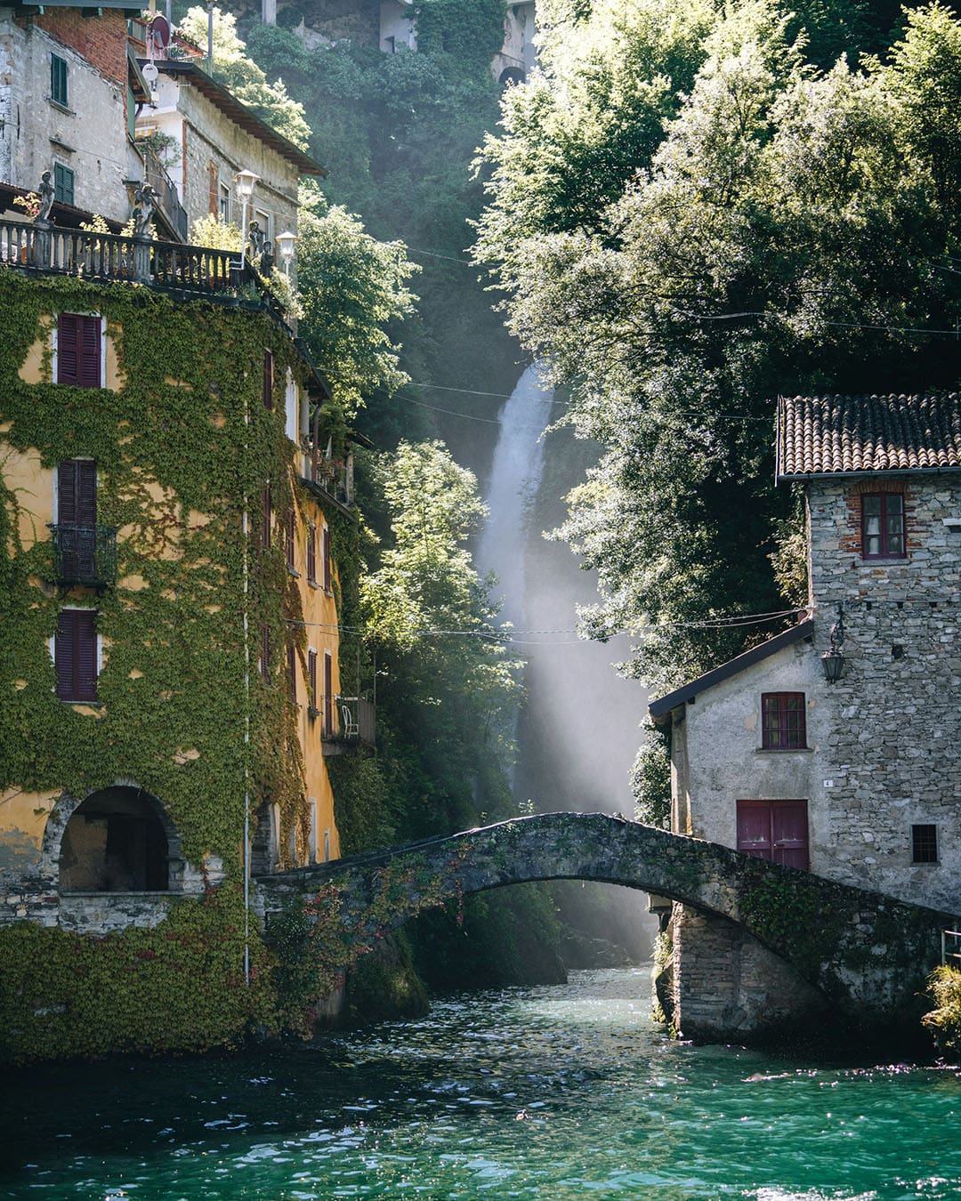 Ancient lakeside buildings either side of a stone footbridge on Lake Como
