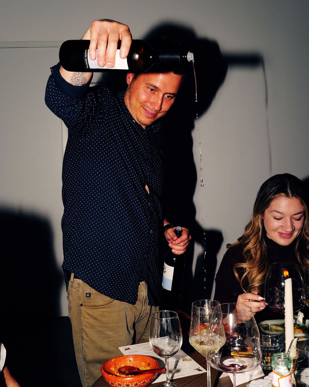 Sommelier Ferdinando Mucerino pours wine from a great height at a lively supper club event hosted by Lele Dinner Club