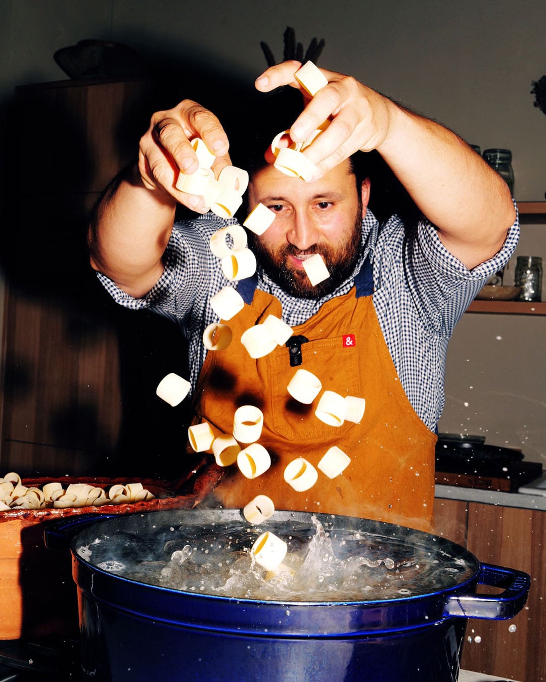 The chef, Daniele Uditi dropping food into a hot pan, from a dynamic angle at ele Dinner Club