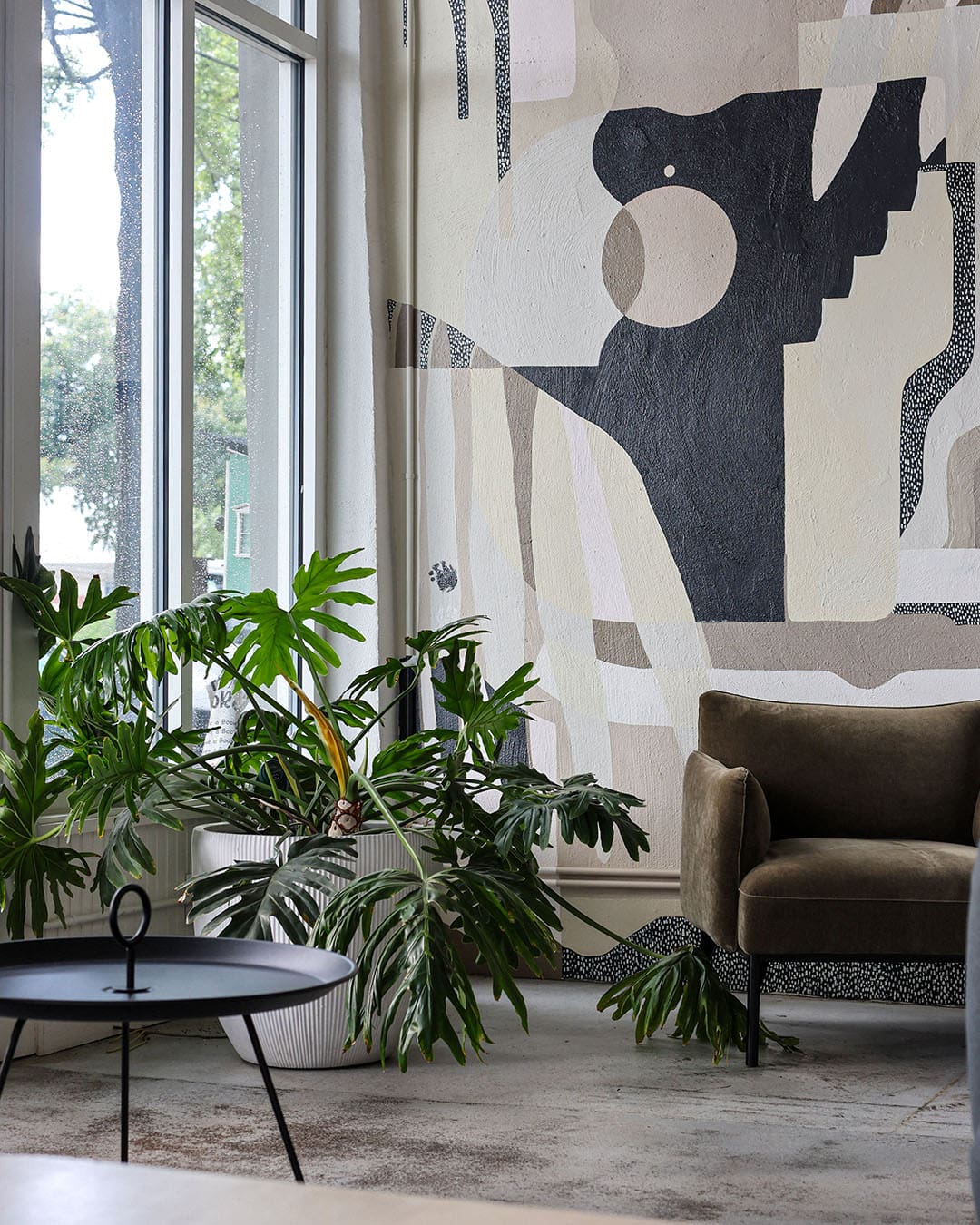 Interiors at Origin Coffee Bar with hand-painted mural and indoor plant in view