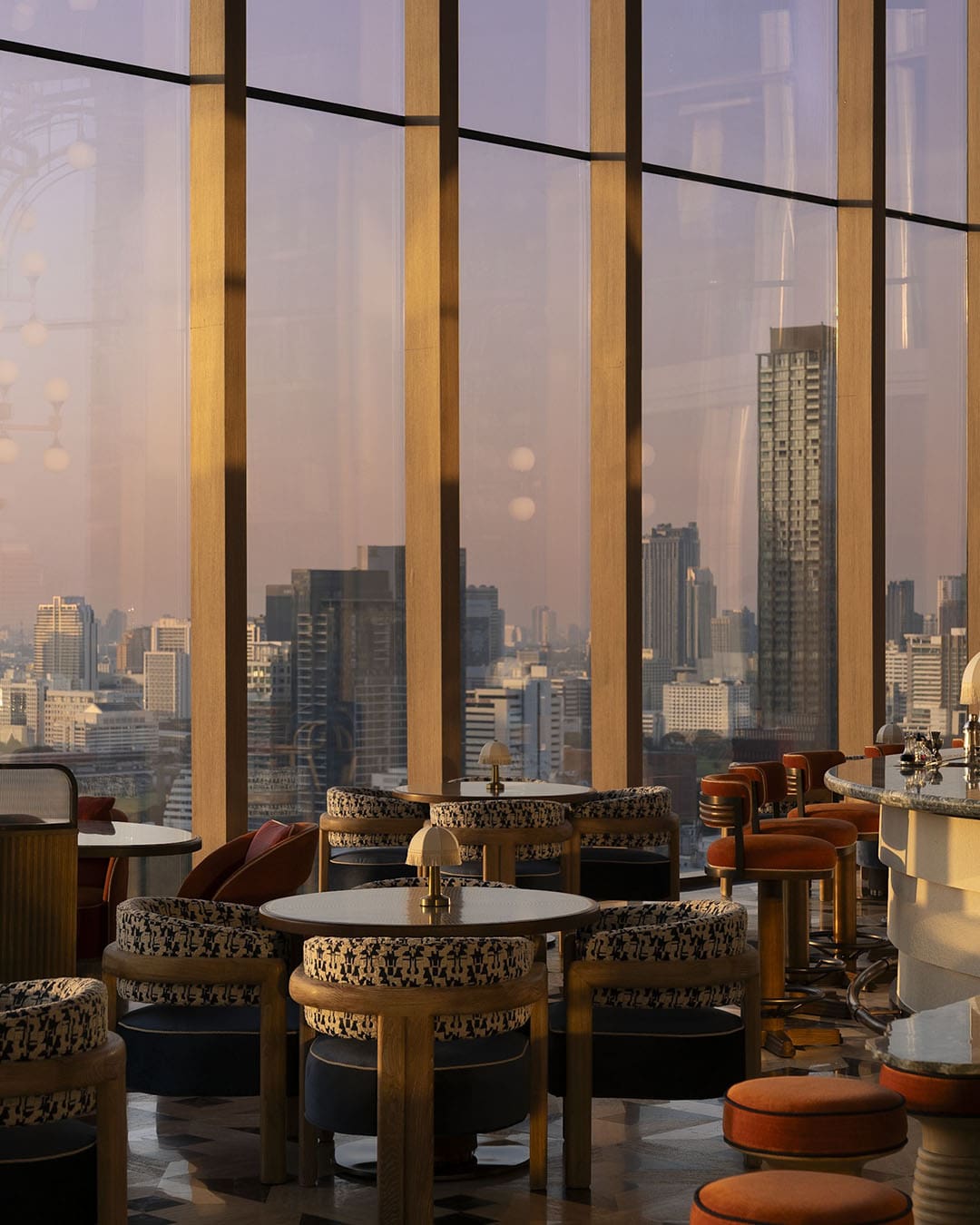 Bar seating in modern hotel overlooking Bangkok skyline at dusk