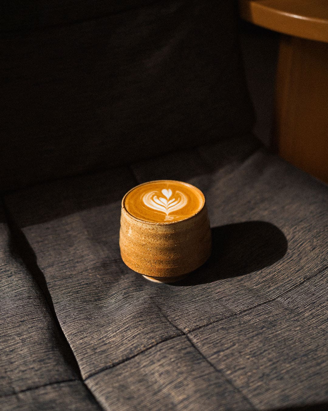 Perfectly designed latte art, a coffee in an earthernware cup resting on material