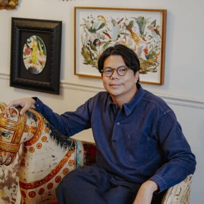 Artist Nakrob in his studio, sitting on an antique horse seat. Photography by Adam Birkan