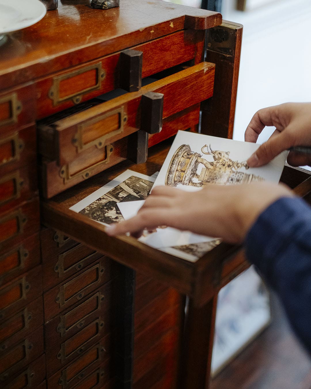 Nakrob Moonmanas looks through some of his artwork collections.Weathered and antique drawers in a cabinet. Photography by Adam Birkan