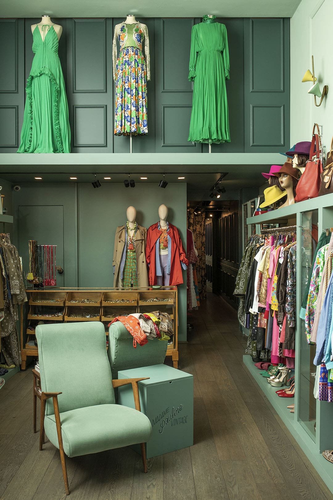 The curated interior of Madame Pauline Vintage. A chair in foreground with fashions surrounding
